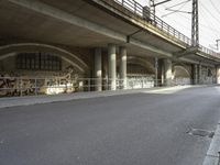 a person riding a skateboard down a street next to a bridge with graffiti on it