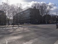 a person riding a skateboard on a street with trees in the distance at an intersection