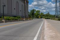 a picture of an empty street that is by some buildings in the distance with trees and bushes in front