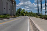 a picture of an empty street that is by some buildings in the distance with trees and bushes in front