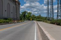 a picture of an empty street that is by some buildings in the distance with trees and bushes in front