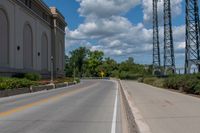 a picture of an empty street that is by some buildings in the distance with trees and bushes in front