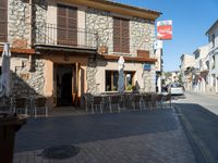 a street view showing old stone buildings and chairs outside of the building with many signs above it