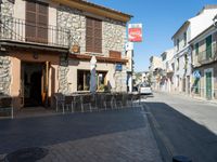 a street view showing old stone buildings and chairs outside of the building with many signs above it