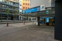 the empty sidewalk outside the station with the entrance sign above and street lights next to it