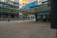 the empty sidewalk outside the station with the entrance sign above and street lights next to it