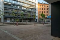 an empty street with two buildings in the background and some trees that have turned red