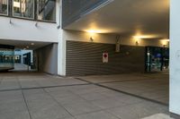 a paved street with large empty shops on the side and a few people walking by