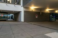 a paved street with large empty shops on the side and a few people walking by