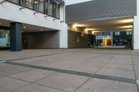 a picture of an empty public space by a building, and a sidewalk with a couple benches on the corner