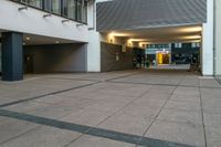 a picture of an empty public space by a building, and a sidewalk with a couple benches on the corner