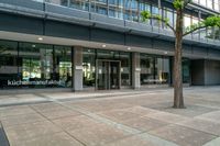 a large building is full of glass doors and some trees in the courtyard area of the building