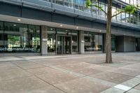 a large building is full of glass doors and some trees in the courtyard area of the building