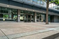 a large building is full of glass doors and some trees in the courtyard area of the building