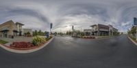 a fisheye shot of two shops by the street with sky in background that has clouds