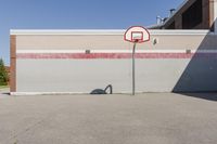 a basketball hoop sits alone in a parking lot next to a building in a suburban neighborhood