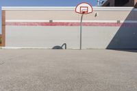 a basketball hoop sits alone in a parking lot next to a building in a suburban neighborhood