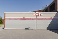 a basketball hoop sits alone in a parking lot next to a building in a suburban neighborhood