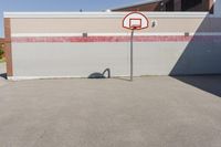 a basketball hoop sits alone in a parking lot next to a building in a suburban neighborhood