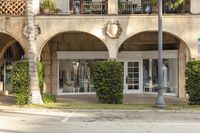 the front of a boutique in front of a tree covered building with a number of mannequin statues