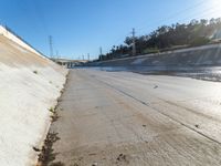 a freeway with concrete walls and water in the middle of it and power lines on the side