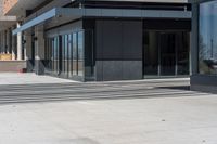 a person wearing a hat is walking outside of a business building that has glass doors and windows