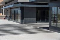 a person wearing a hat is walking outside of a business building that has glass doors and windows