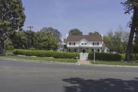 there is an old white house in the suburbs of california on this street that looks great with a lot of grass and bushes