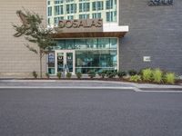 the parking lot in front of the building has signage and a building with a tree