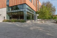 there is a clock that is on the ground outside of this building and is in front of some trees