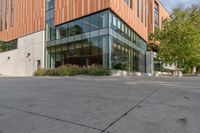 there is a clock that is on the ground outside of this building and is in front of some trees