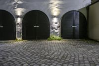 a stone and brick wall with black double doors and a lamp fixture in the middle