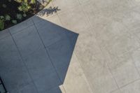 a close up view of a concrete walkway from above, on a patio in a suburban area with a wooden bench and concrete planter