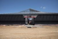 a man standing next to a black building that is under construction with large openings above it