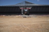 a man standing next to a black building that is under construction with large openings above it