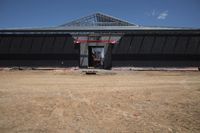 a man standing next to a black building that is under construction with large openings above it