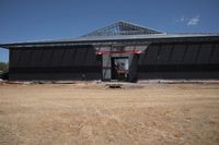 a man standing next to a black building that is under construction with large openings above it