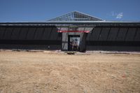 a man standing next to a black building that is under construction with large openings above it