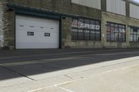 the man riding a scooter down a street in front of a factory building