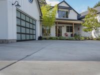 a home that has two garages in front of it, and the outside is grey and there are bushes in front