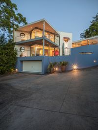 a two story home with a long driveway lit by the night lights from the outside