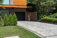 a driveway leading to a house with a concrete patio and lawn areas next to the entry