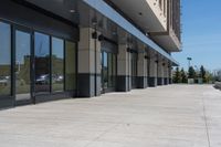 a building with two rows of glass doors, outside and on side of walkway and pavement