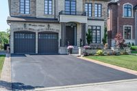 a home on the corner with driveways and a house behind it with garage door