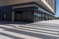 two people walking down a sidewalk near an empty building with large windows and glass walls