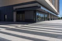 two people walking down a sidewalk near an empty building with large windows and glass walls