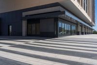 two people walking down a sidewalk near an empty building with large windows and glass walls