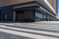 two people walking down a sidewalk near an empty building with large windows and glass walls