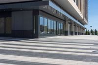 two people walking down a sidewalk near an empty building with large windows and glass walls