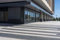 two people walking down a sidewalk near an empty building with large windows and glass walls